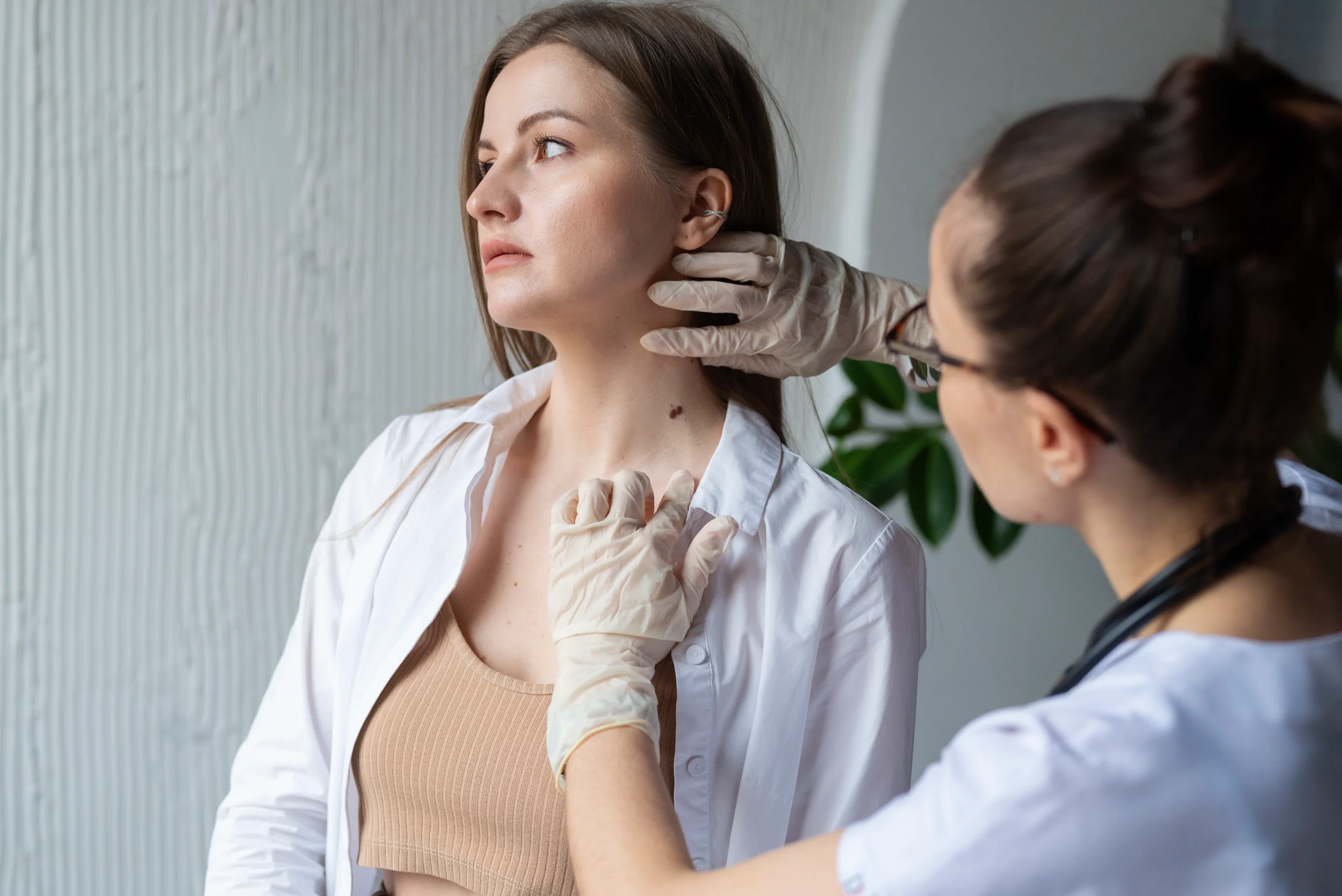 Aesthetic specialist examining patient’s neck during professional skin tag removal consultation in a clinical setting.